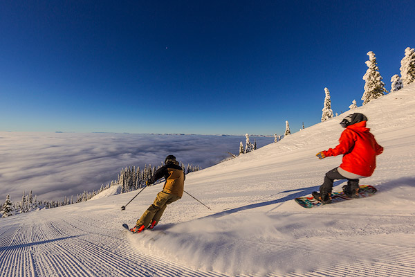 Skier and snowboarder down the fresh groom on Inspiration at Whitefish Mountain Resort in Whitefish, Montana, USA model released