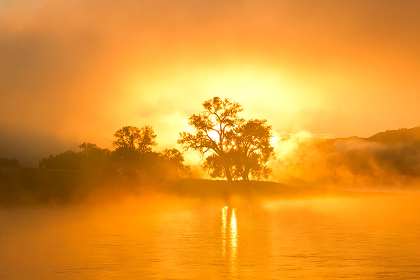 Morning sunrise burns through the fog on the Missouri River at the Upper Missouri River Breaks National Monument, Montana